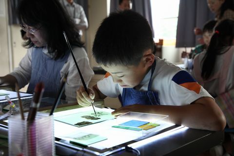 熱心に筆を動かし、ガラスに絵付けをする児童の写真