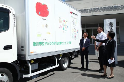 児童の絵のラッピングを施した給食配送車を紹介する曽我小学校の田中浩美校長