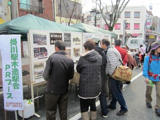 新春ウォーキングで掛川駅木造駅舎PRブースに立ち寄り、熱心に写真を見る参加者ら