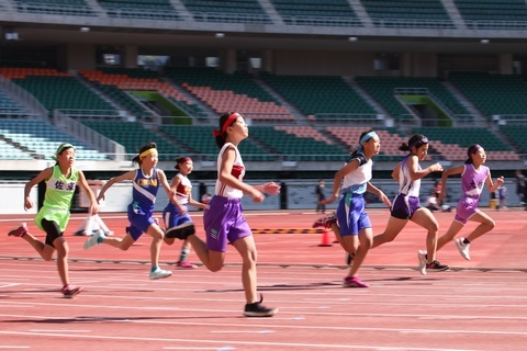 掛川市小学校陸上競技大会で選手たちが色とりどりのハチマキとユニフォームでトラックを走っている様子