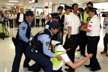 駅構内で合同訓練で訓練のためにゼッケンを付けているファン役の男性と抱え上げる警察官らの様子。