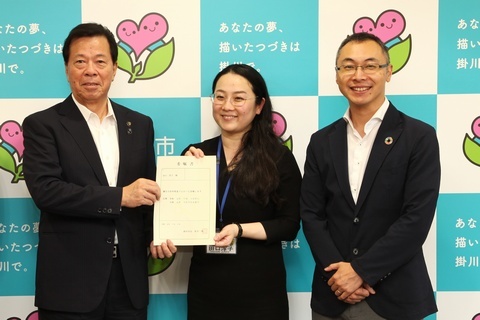 委嘱書を披露する女性と松井市長と男性の写真。
