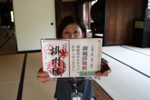 女性が御城印を広げて見せている