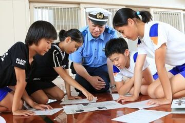 警察官を囲んで地域の危険個所や事例を共有する児童4人の写真