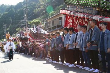 屋台の前に立つ氏子たちがおじぎをして神輿渡御を迎えている