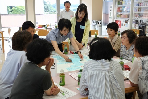 資料やメモを書いた付箋を机に並べて話し合う参加者たち