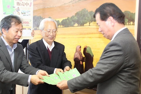 松井市長に緑茶色をしたA6サイズのパスポートを披露する八木さんと杉浦さん