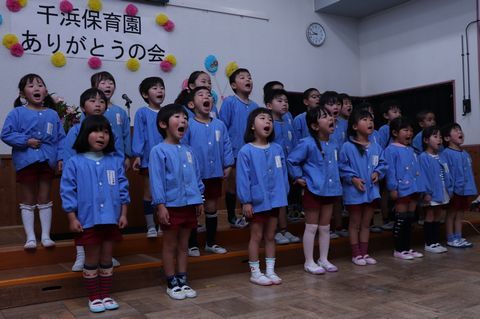 千波保育園ありがとうの会の飾りの前で、大きな口を開けて合唱する園児たち