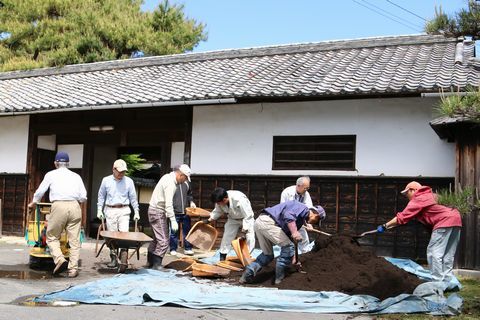 山盛りの土をボランティアたちが運んでいる様子