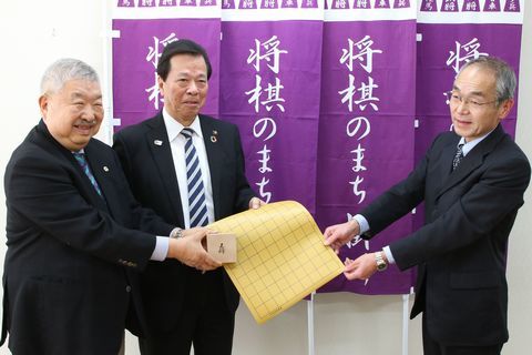 窪野校長が松井三郎会長と松本巌会長から将棋セット受け取っている様子の写真