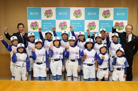 ガッツポーズで記念写真を撮る桜木女子ソフトボール部の選手たちと松井市長と佐藤教育長