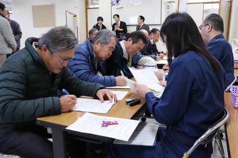 受付で書類に記入する参加者とそれを確認する人たち