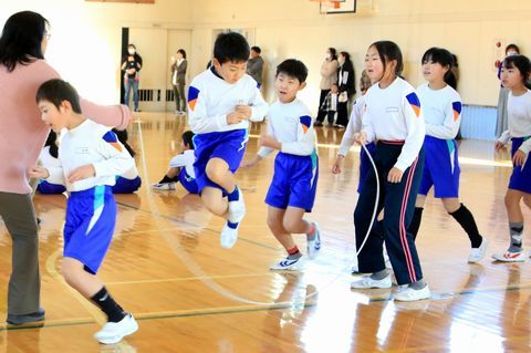 タイミングを合わせて高く飛ぶ児童と順番を待つ児童たち