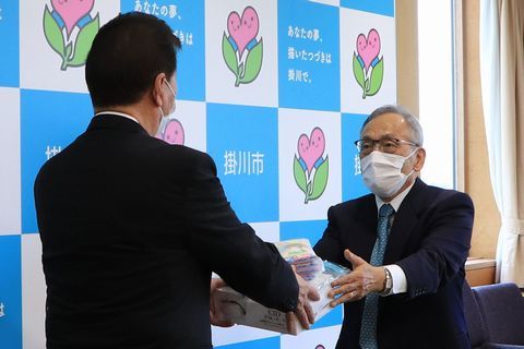松井市長に感染防止用品を手渡すマスク姿のアイエル代表取締役石川さんの写真