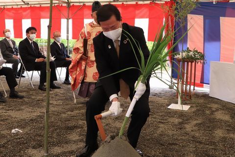 鎌を持ち安全祈願祭で刈り初めの儀を行う松井市長の写真