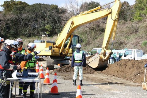 建設業者が支持を出しながらショベルカーで土砂を撤去する様子