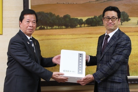 松井市長が丸山代表取締役から給水器を受け取っているようす
