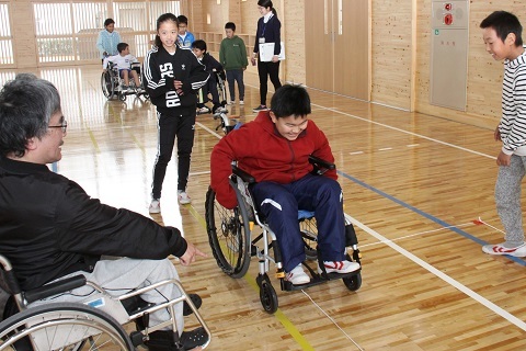 車いすに乗った横山さんから車いすの動かし方を教わる児童