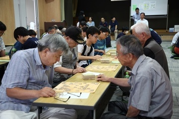 子どもからお年寄りまでが、将棋交流会で並んで対局する様子。