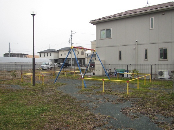 鷺田北公園の様子、アスファルトの地面に安全柵で囲われたブランコが設置されている