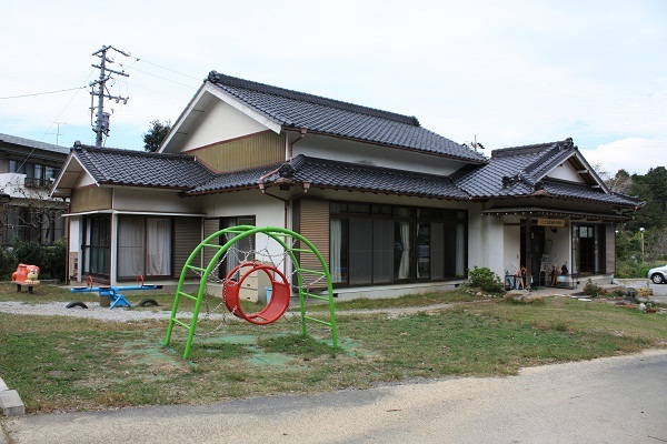 桜木小学童保育所の様子、一軒家の芝生の庭に、アスレチック遊具、シーソーなどが設置されている