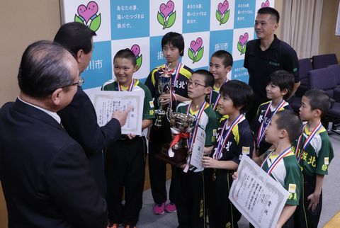 松井市長と佐藤教育長の前で整列し優勝を報告する選手たち