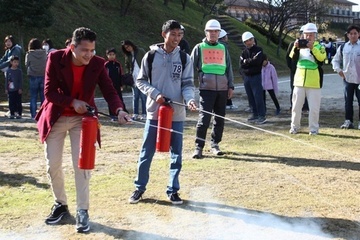 消火訓練で水消化器を火元へ向けて放つ二名の外国人留学生