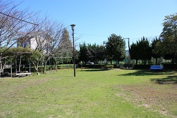 ブランコとベンチと屋外灯がある、芝生が広がる公園