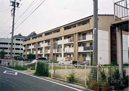 道路に面して建っている茶色のマンションと駐車場