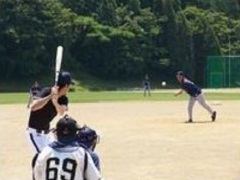 大須賀運動場で、バッターが構え、ピッチャーがボールを投げている写真