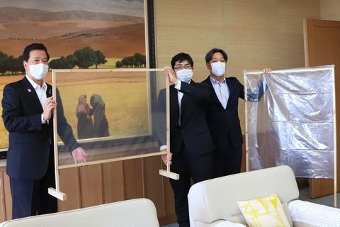 飛まつ防止パーテーション考案者の鳥谷さんがパーテーションを松井市長へ手渡している様子