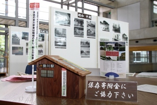 パネル展示の前に、保存寄附金に協力を求める看板と駅舎を模した募金箱が置かれている。