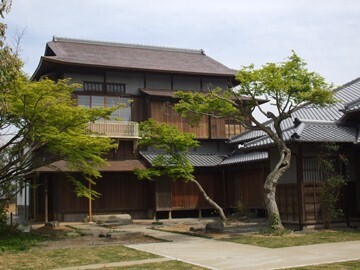 二階建ての古い屋敷で、その手前に木が植わっている