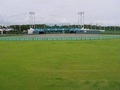 芝生の奥にナイター設備のある野球場が見える、大東総合運動場の様子