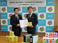 協定締結式で松井市長とUCC上島珈琲株式会社の大内取締役が協定書を持っている写真