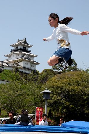 掛川城天守閣をバックにジャンプする女子児童
