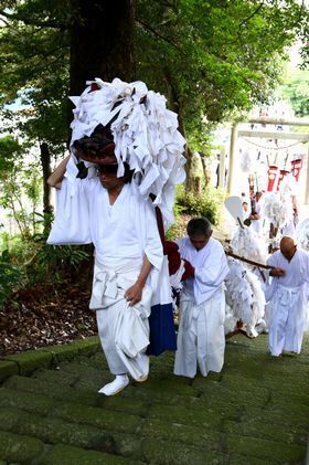 白い衣装を着た獅子の役割の男性がが六所神社の石段を上る獅子