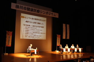 掛川市健康医療シンポジウム開催会場壇上左側に講師の篠原彰先生と右側にパネリスト４名の方達でパネルディスカッション中