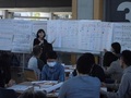 参加者の前に立ち、ホワイトボードに貼られた模造紙を使って話している女性の写真