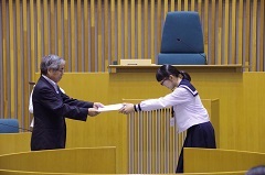 女子生徒が議長から任命証書を受け取っている様子