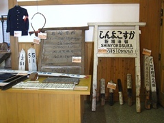 駅表、名所案内板、駅員の制服などを並べて展示している様子。