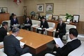 7人の男性が椅子に座り、紙に目を通している写真
