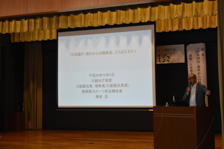 壇上でプロジェクターを見せながら講演する溝端宏氏