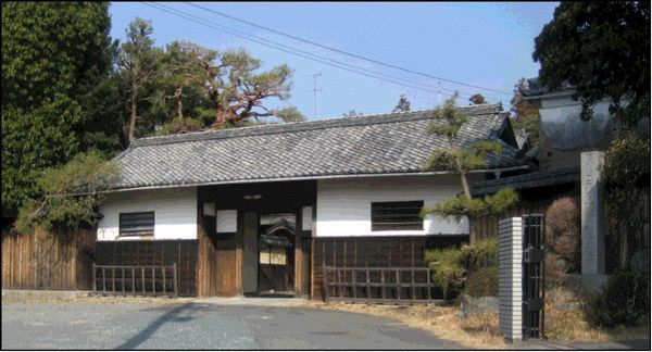 右側に明治天皇行在所の碑がある、松ヶ岡正門（長屋門）の外観写真