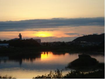空をオレンジ色に染める夕日と、川の水面に夕日が映っている様子。