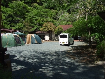 山の手前にある分校跡地。キャンプ用のテントがはられ、車も停まっている。