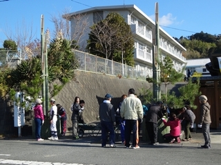 小学6年生と学校教職員と地域ボランティアとPTA理事らが高さ6メートルほどあるジャンボ門松づくりの飾り付けなどをする様子