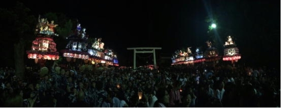 きれいに装飾されたねりの提灯の明かりが、夜の暗闇のなかで輝き幻想的である。祭りにたくさんの人が来ている様子が見られる。熊野神社境内千秋楽の様子